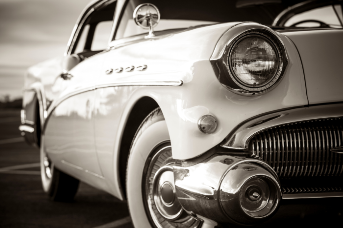Close-up of a vintage car's chrome headlight and front grille