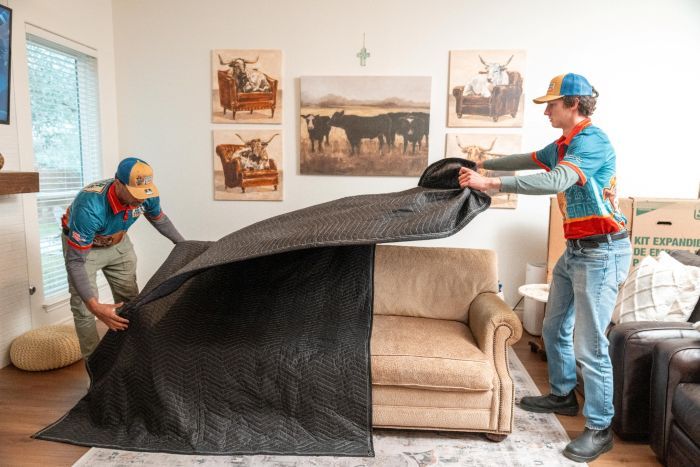 Movers covering a sofa with a protective blanket during a home move