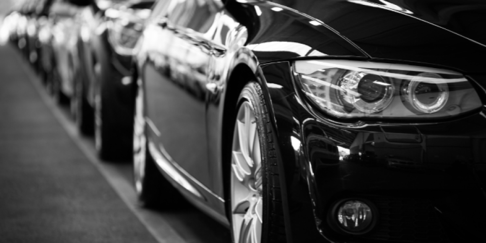Black and white close-up of a row of parked luxury cars