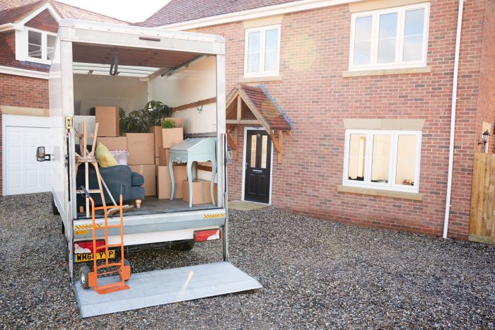Loaded moving truck backed up to a house with furniture and boxes inside