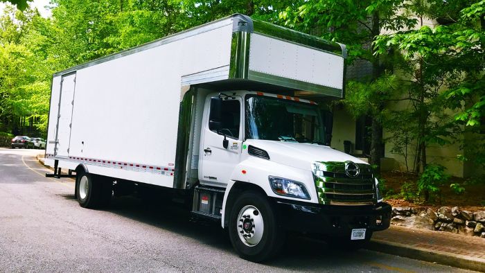 White box truck loaded for a long distance move, parked outside a residential building