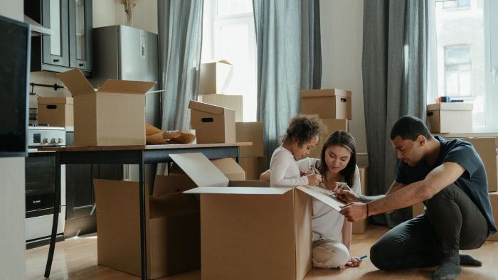Family of 3 packing boxes for their upcoming move.